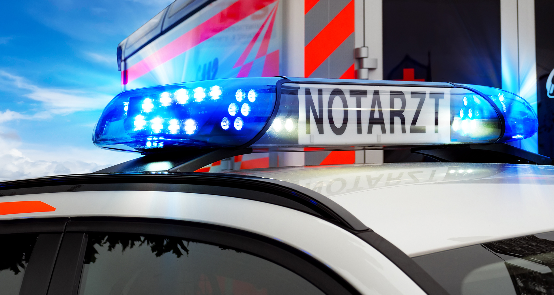 Teilansicht Feuerwehreinsatzfahrzeug mit Blaulicht und Notarztfa
